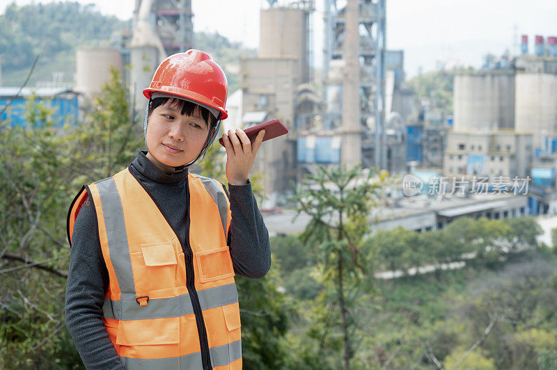 A female worker uses her mobile phone to communicate in a cement plant